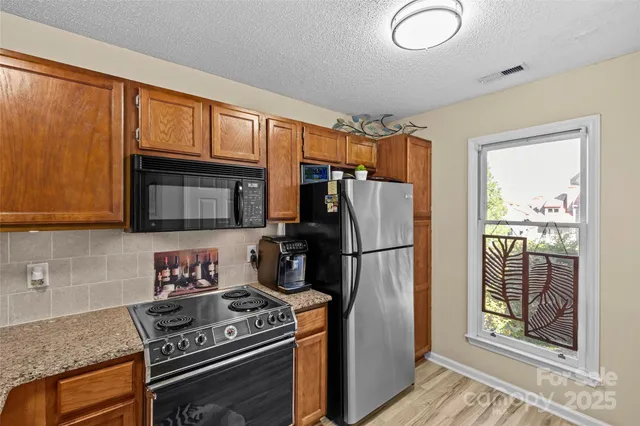 a kitchen with a refrigerator a stove top oven cabinetry and a window