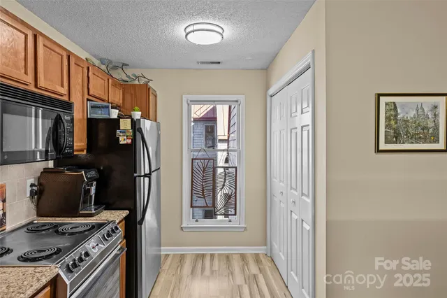 a view of a kitchen with fridge and wooden floor