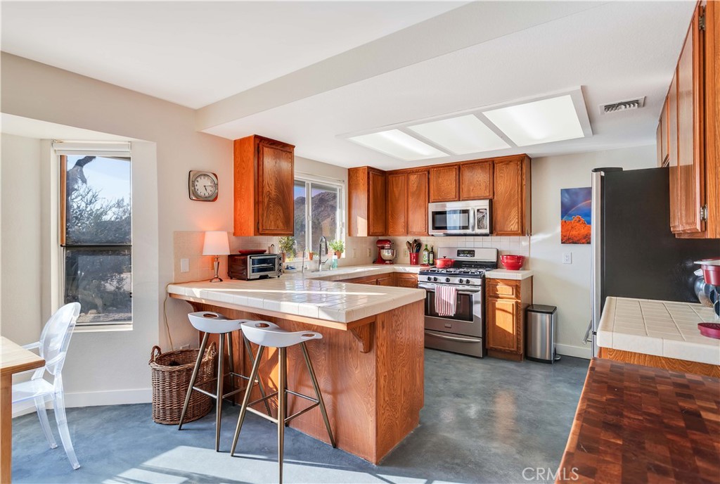 8775 Desert Shadow Road Joshua Tree, CA 92252 - Photo 13 of 39 a kitchen with stainless steel appliances granite countertop a stove top oven a sink dishwasher and a refrigerator