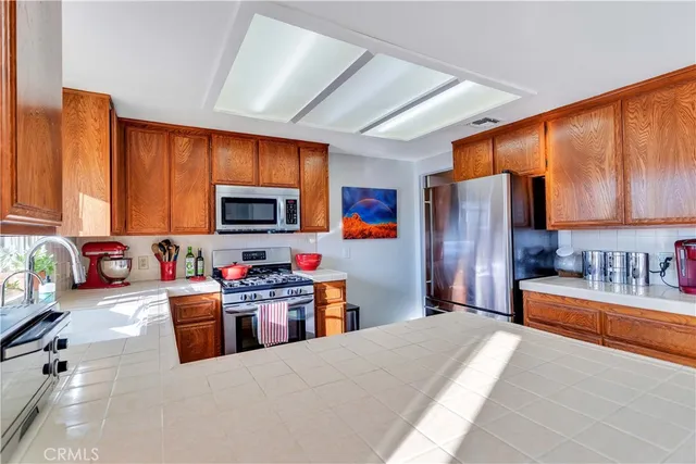 a large kitchen with stainless steel appliances granite countertop a refrigerator stove top oven a sink and dishwasher