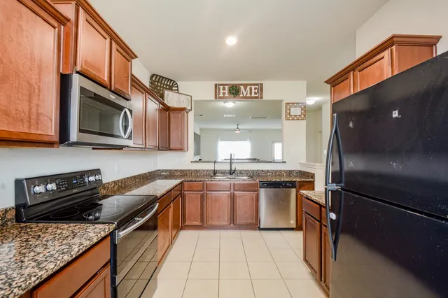a kitchen with stainless steel appliances granite countertop a stove refrigerator and a sink