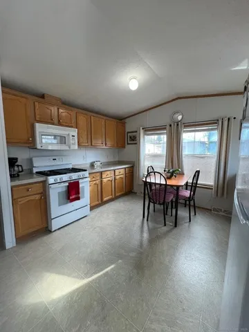 a kitchen with stainless steel appliances granite countertop a stove top oven a sink a dining table and chairs with wooden floor