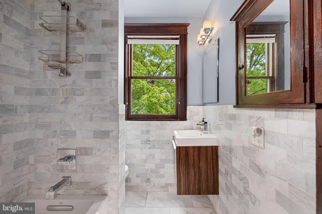 a bathroom with a sink a bathtub and next to a window