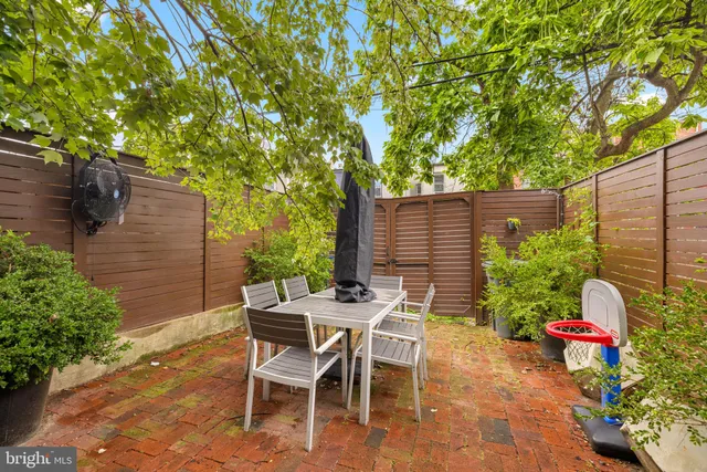 a patio with table and chairs and potted plants