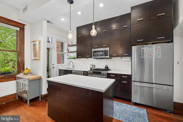 a kitchen with kitchen island a counter top space a sink stainless steel appliances and cabinets