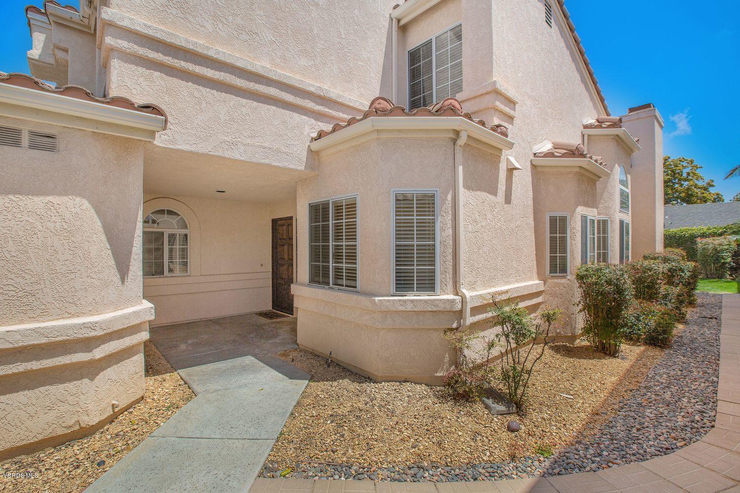 2188 Eastridge Loop Oxnard, CA 93036 - Photo 2 of 27 a view of a white house with large windows and a table and chair