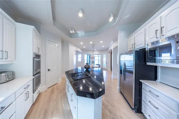 a large white kitchen with stainless steel appliances granite countertop a lot of counter space a refrigerator and a stove top oven