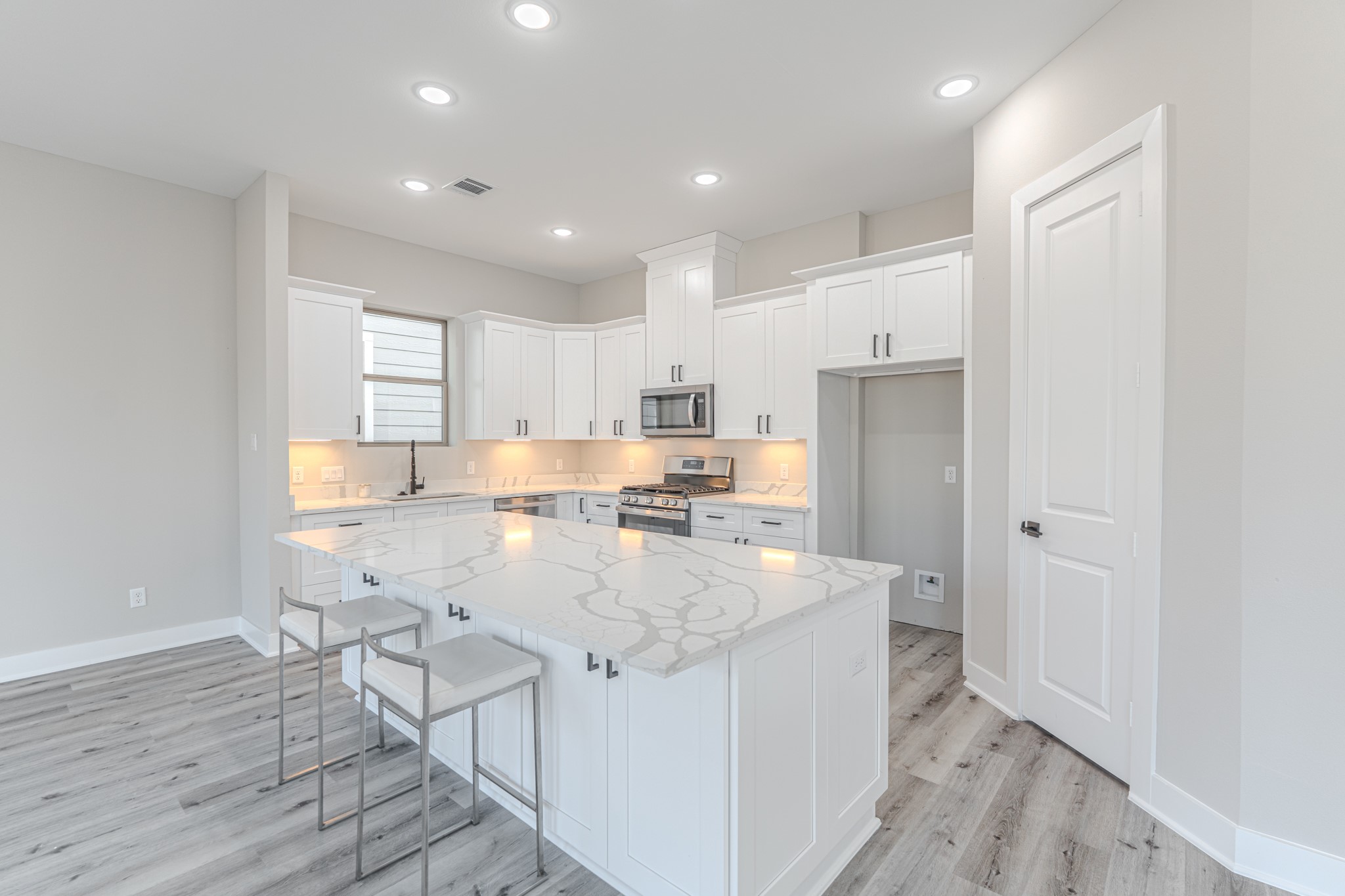 4910 Wunder Way Houston, TX 77069 - Photo 20 of 49 a large kitchen with kitchen island a stove a sink a refrigerator and white cabinets with wooden floor