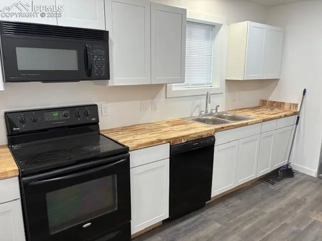 a view of a refrigerator in kitchen and an empty room with wooden floor