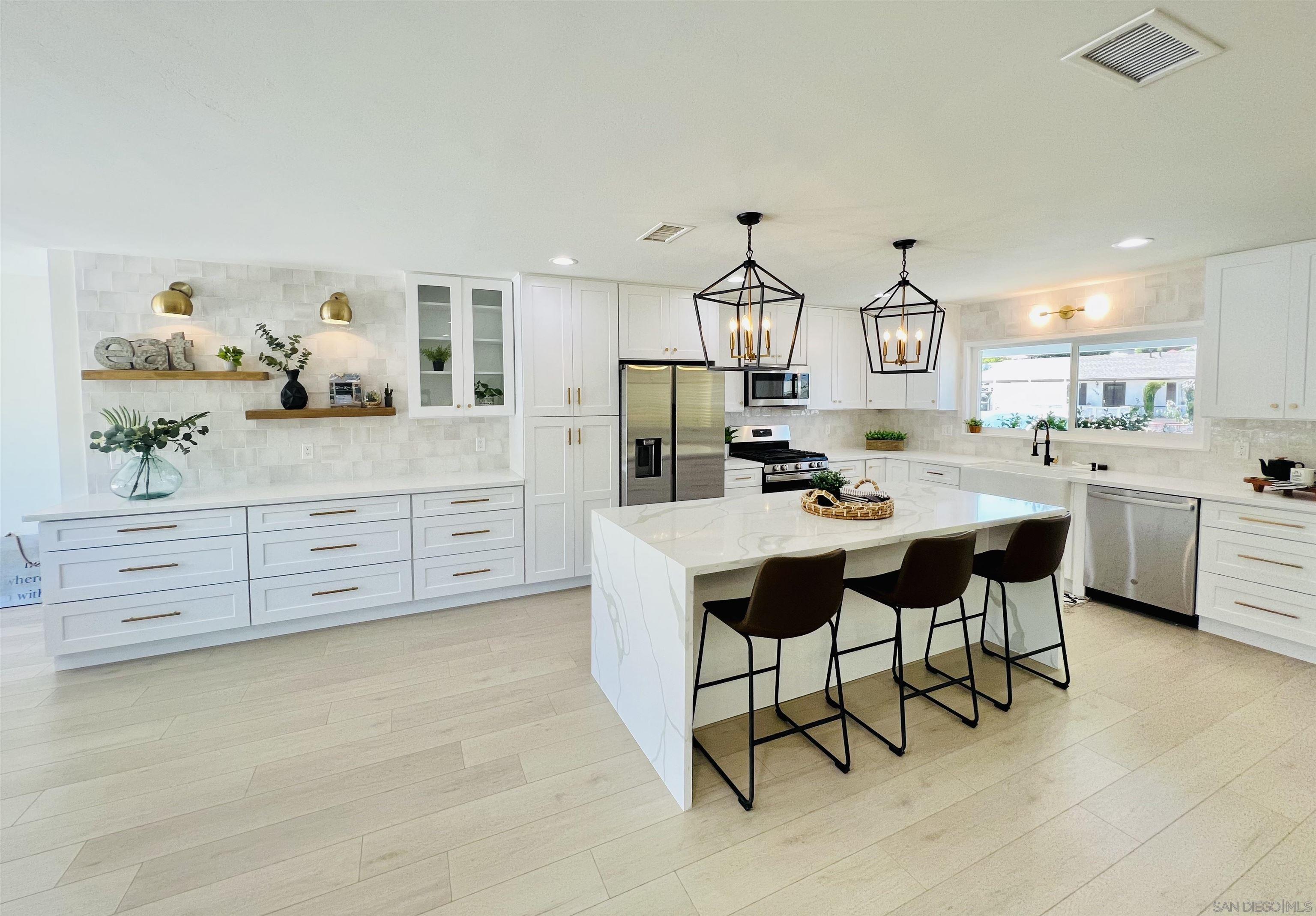 a kitchen with stainless steel appliances kitchen island granite countertop a table chairs sink and cabinets