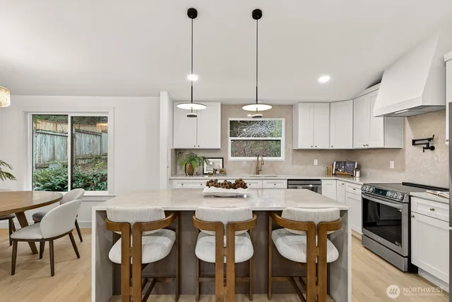 a kitchen with stainless steel appliances kitchen island a table chairs sink and cabinets