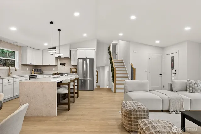 a large white kitchen with a refrigerator a stove a sink and a fireplace