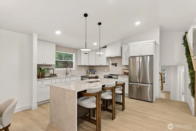 a kitchen with a refrigerator a stove a sink and chairs