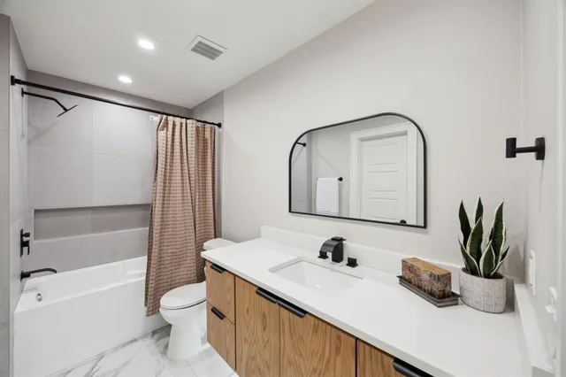 a bathroom with a granite countertop sink mirror vanity and toilet