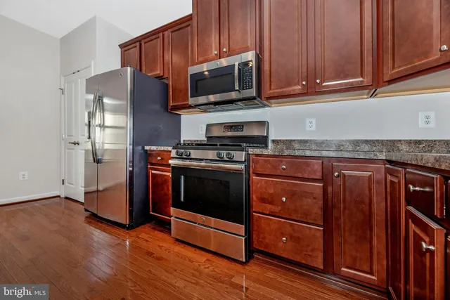 a kitchen with granite countertop wooden cabinets stainless steel appliances and a sink