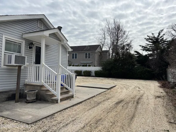 a view of a house with a wooden bench next to a yard