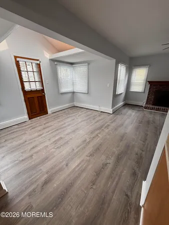 a view of an empty room with window and wooden floor