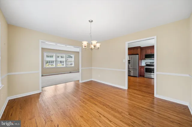 an empty room with wooden floor chandelier and windows