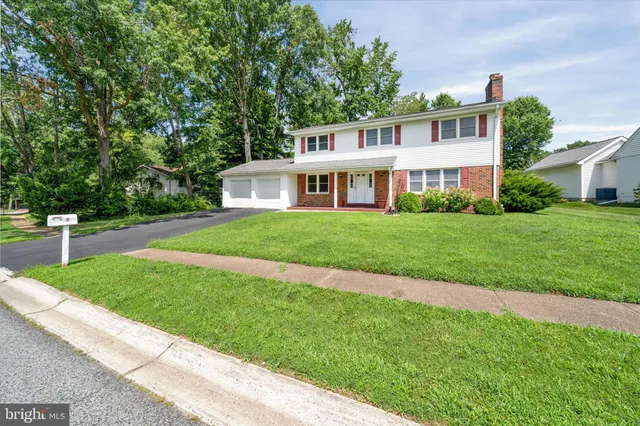 a view of a house next to a big yard and large trees
