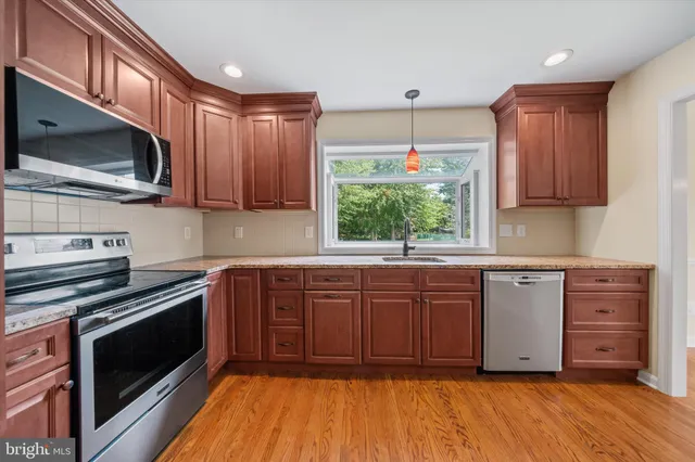 a kitchen with stainless steel appliances granite countertop a stove a sink and a microwave