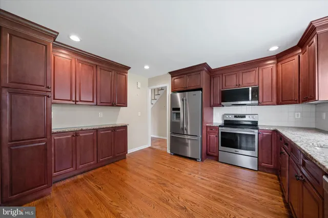 a kitchen with stainless steel appliances granite countertop a refrigerator stove and wooden cabinets