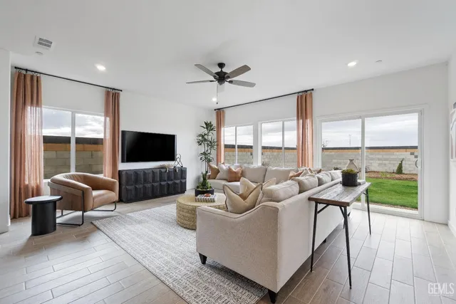 a living room with furniture floor to ceiling window hardwood floor and a flat screen tv