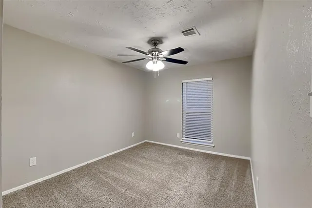 a view of an empty room with a ceiling fan and window