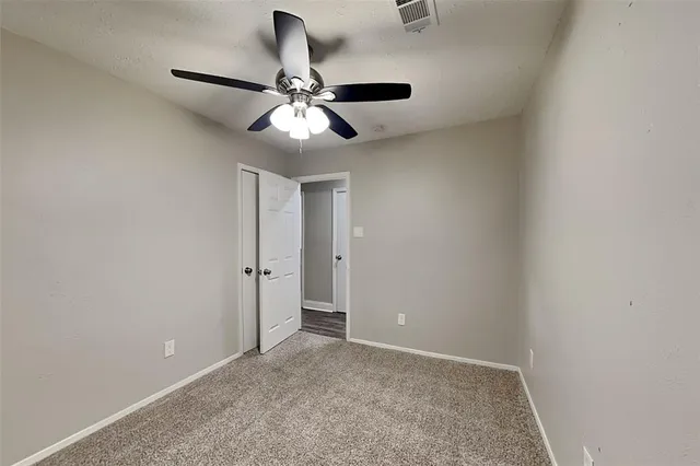 an empty room with a chandelier fan and windows