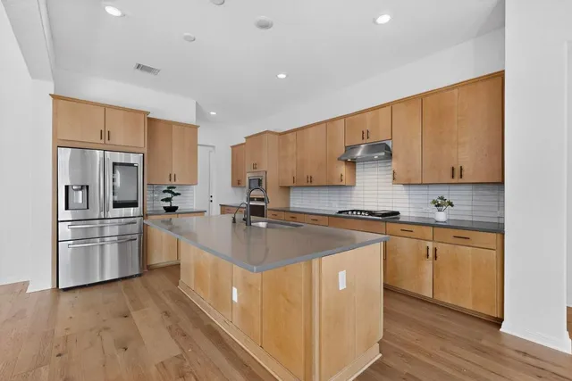 a kitchen with stainless steel appliances granite countertop a sink stove refrigerator and cabinets