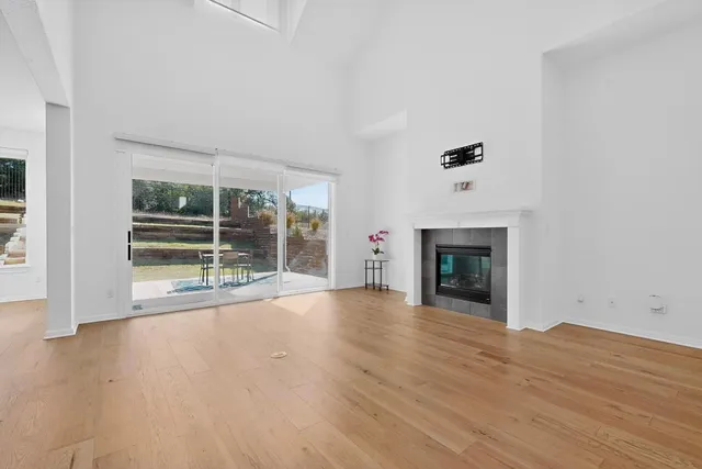 an empty room with wooden floor fireplace and windows