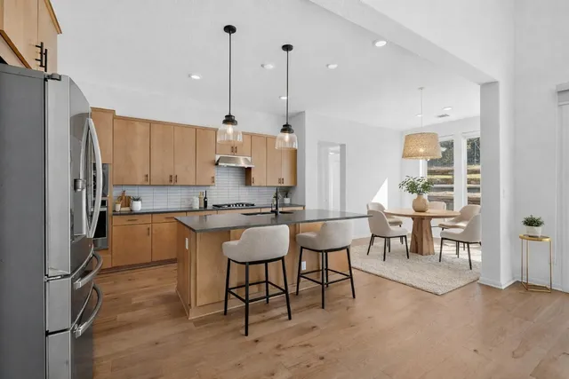 a kitchen with kitchen island a dining table chairs stainless steel appliances and cabinets
