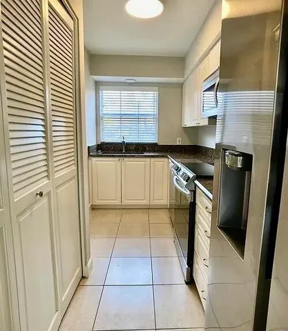a kitchen with a sink a refrigerator and cabinets