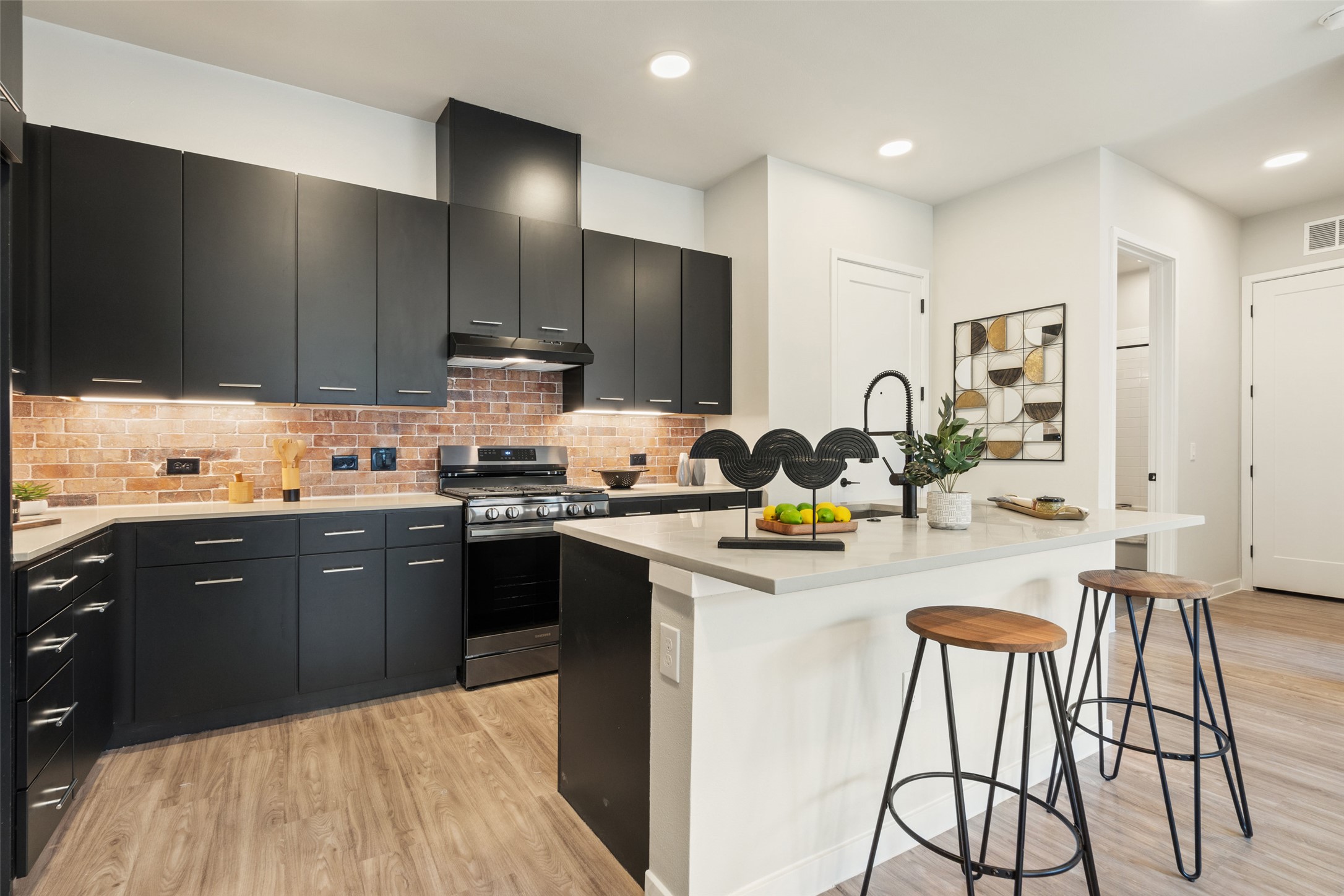 4510 Terry-O Lane, Unit 341 Austin, TX 78745 - Photo 12 of 40 The kitchen features matte black cabinetry, a brick-style backsplash, stainless steel appliances, and an island with a light-colored countertop