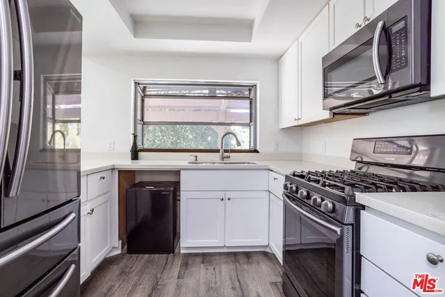 a kitchen with stainless steel appliances white cabinets granite counter tops and a wooden floor