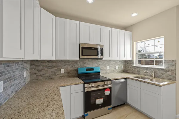 a kitchen with stainless steel appliances granite countertop a stove a sink and a microwave
