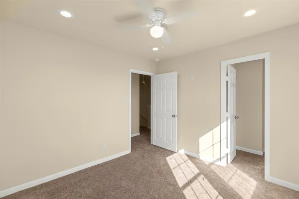 an empty room with wooden floor and a ceiling fan