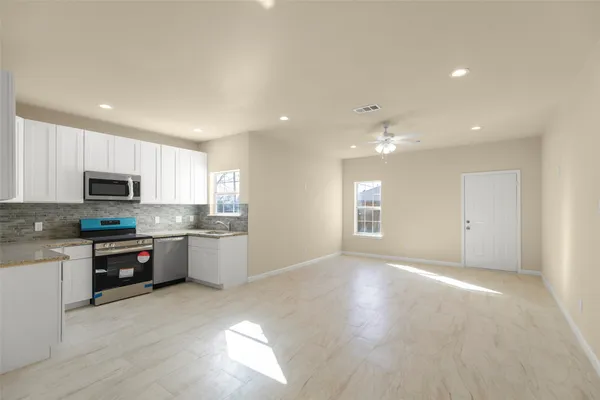 a large kitchen with stainless steel appliances granite countertop a stove a sink dishwasher and a microwave oven with white cabinets