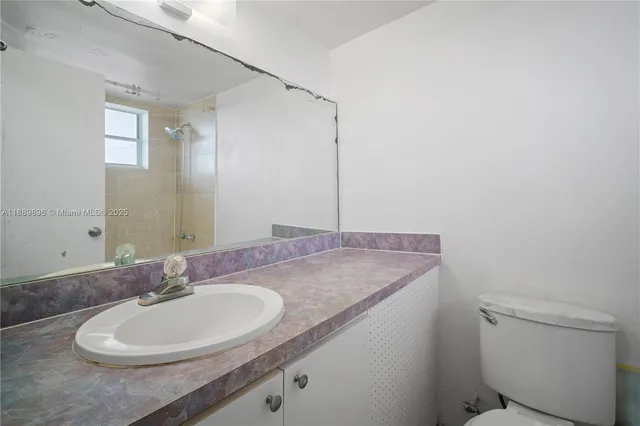 a bathroom with a granite countertop sink a mirror and a toilet