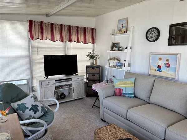 a living room with furniture a flat screen tv and a window