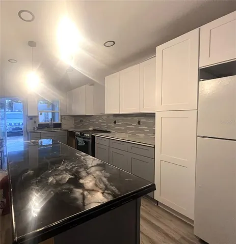 a kitchen with stainless steel appliances granite countertop a refrigerator a stove and a sink