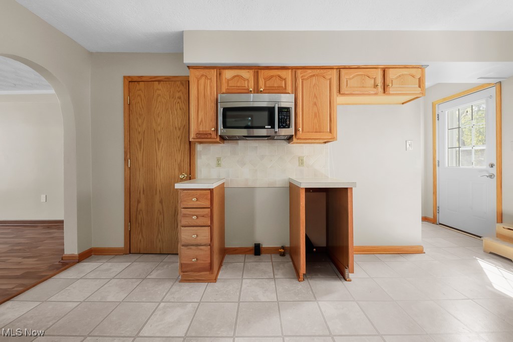 1702 Far View Road Akron, OH 44312 - Photo 14 of 49 Kitchen featuring arched walkways, backsplash, light countertops, stainless steel microwave, and light tile patterned flooring
