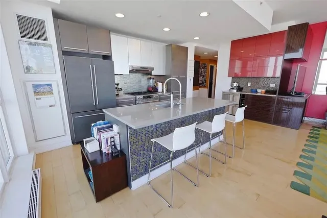 a large kitchen with stainless steel appliances granite countertop a refrigerator a stove a sink and a dining table with wooden floor