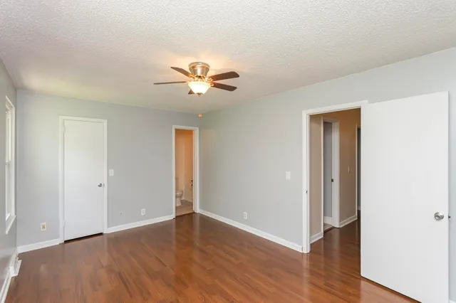 an empty room with wooden floor and a ceiling fan