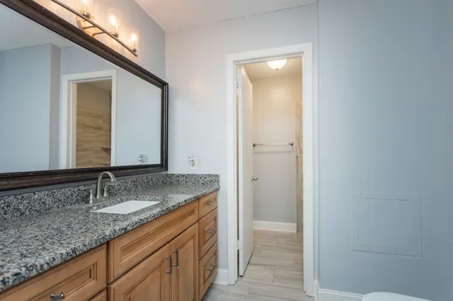 a bathroom with a granite countertop sink and a mirror