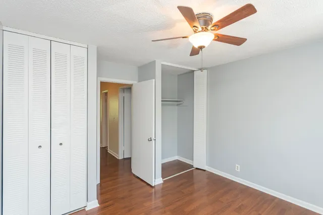 an empty room with wooden floor and ceiling fan