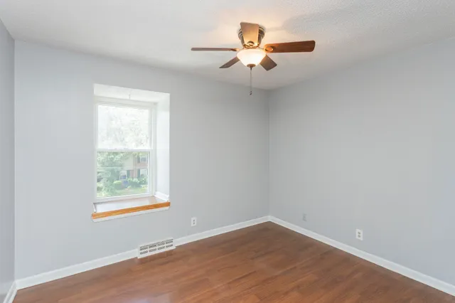 an empty room with a window and a fan