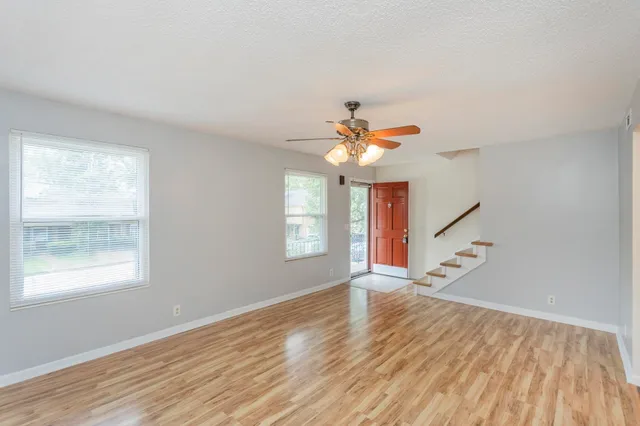 a view of an empty room with wooden floor and a window