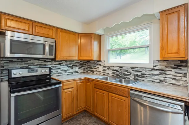 a kitchen with granite countertop a sink stainless steel appliances and cabinets