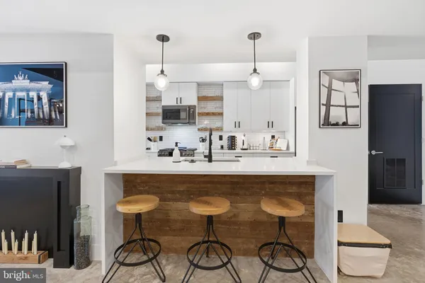 a dining table chairs white cabinet and a microwave