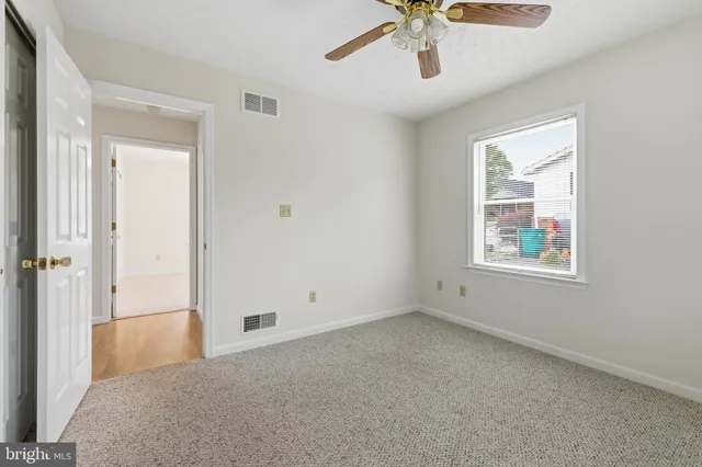 a view of an empty room and chandelier fan